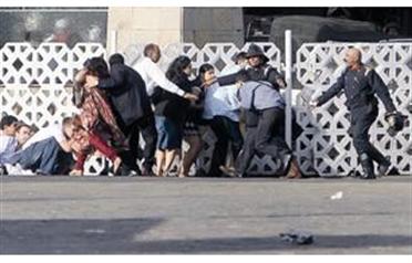 People run for cover as gunshots are fired from inside the Taj Mahal hotel in Mumbai. (REUTERS)