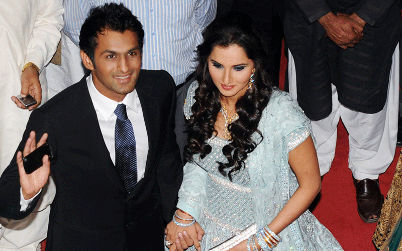 Indian tennis star Sania Mirza (R) holds her husband and Pakistani cricketer Shoaib Malik's hand as they arrive at their wedding reception in Lahore on April 27, 2010. Newlywed and hailed as cross-border peace ambassadors, Mirza and Malik arrived in Pakistan on April 22 to a frenzied reception.  (AFP)