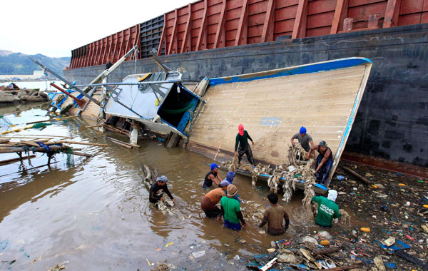 Filipino fishermen retrieve their belongings after their fishing boat was damaged along the coast of Mariveles town, Bataan province, west of Manila, Philippines a day after Typhoon Conson hit the country.At least 23 people were confirmed dead in the aftermath of Typhoon Conson,the National Disaster Coordinating Council (NDCC) said. (EPA)