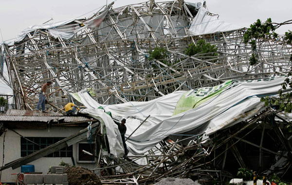 Filipino workers try to dismantle a billboard that collapsed due to strong winds from Typhoon Conson in  Muntinlupa, south of Manila, Philippines.The first typhoon to lash the Philippines this year killed several people and left some 11 others missing Wednesday after flooding streets in the capital and toppling power lines.(AP)