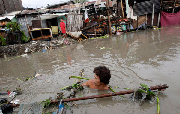 A Filipino resident tries to salvage his submerged boat in Las Pinas city, south of Manila,Philippines. (EPA)