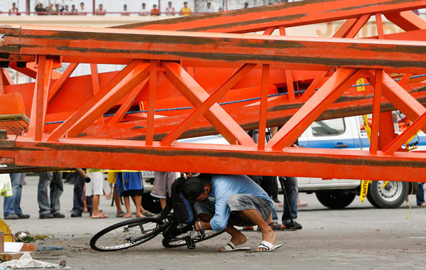 A Filipino crosses under the beams of a collapsed crane brought down by strong winds from Typhoon Conson at the South Luzon Expressway in Paranaque city, south of Manila, Philippines.(EPA)