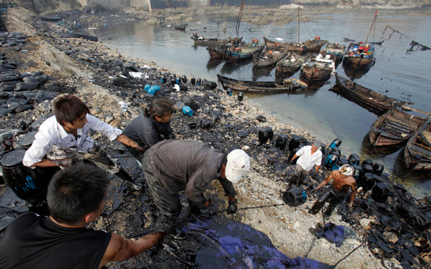 Local fishermen clean up oil near an oil spill site in Dalian, Liaoning province. A chemical agent used to strip sulphur from oil contributed to the pipeline blast at China's Dalian port last weekend, causing the huge oil slick in the sea and forcing the port's temporary closure, the country's work safety watchdog said in a preliminary report. (REUTERS)