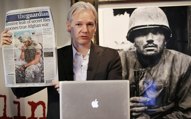 Julian Assange of the WikiLeaks website holds up a copy of The Guardian newspaper as he speaks to reporters in front of a Don McCullin Vietnam war photograph at The Front Line Club in London, England. The WikiLeaks website has published 90,000 secret US Military records. The Guardian and The New York Times newspapers and the German Magazine Der Spiegel have also published details today. (GETTY IMAGES)