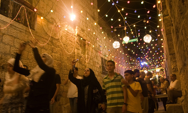 Palestinians walk under colored lights as they go to the first evening prayers at the al-Aqsa mosque at Jerusalem's old city Damascus Gate after breaking the fast on the first day of the Moslem holy month of Ramadan. (AFP)