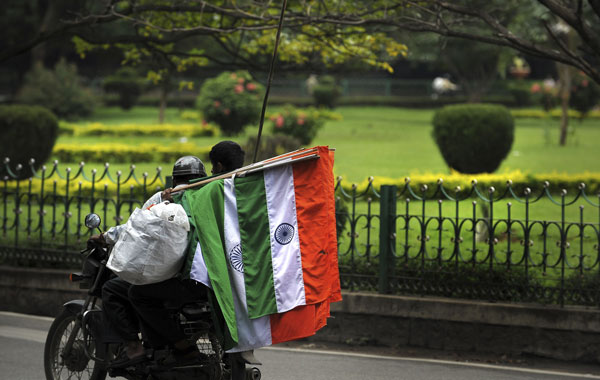 An Indian street vendor sitting as a pillion on a motorcycle holds national flags for sale at a busy intersection in Bangalore. (AFP)