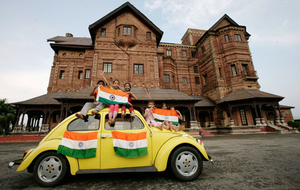Children hold Indian national flags as they sit on a car during a photo-shoot in front of Hari Palace during the Independence Day celebrations in Jammu August. (REUTERS)