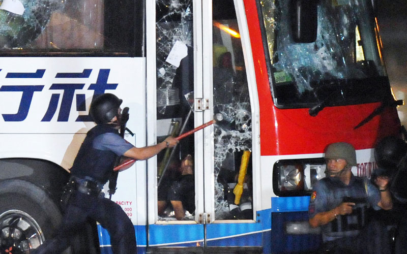 Philippine policemen try to open the door of a tourist bus hijacked in Manila. (AFP)