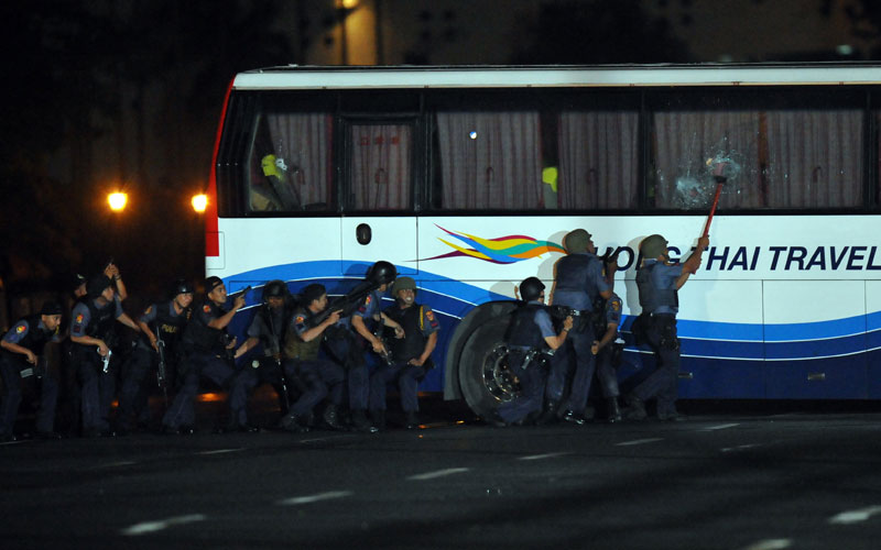 Philippine policemen take position as they start their attack on a tourist bus hijacked in Manila. (AFP)