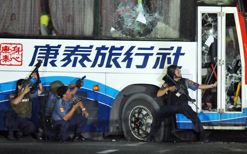 Philippine policemen take position as they start their attack on the tourist bus hijacked in Manila. The hostage-taking in the Philippines capital ended with six bus passengers dead after shots rang out and police stormed the vehicle. Police the hostage-taker also died. (AFP)