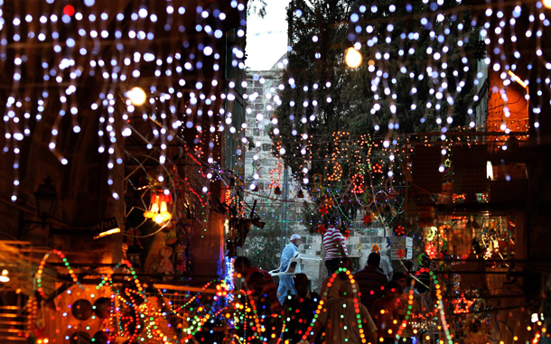 An Arab man carries a chair to the evening prayer in the Al Aqsa compound, while in the foreground people stroll through a during Ramadan colorful lit market street in Jerusalem's Old City. (EPA)