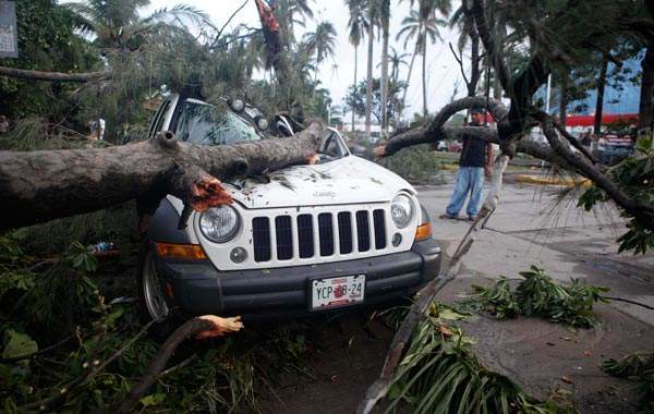 A man stands next to a vehicle damaged by a fallen tree due to the passage of Hurricane Karl in Veracruz, Mexico. (AP)