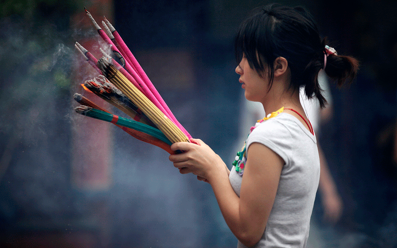 A visitor prays as she burns joss sticks at the City God Temple in Shanghai on the Mid-Autumn Festival. (AP)