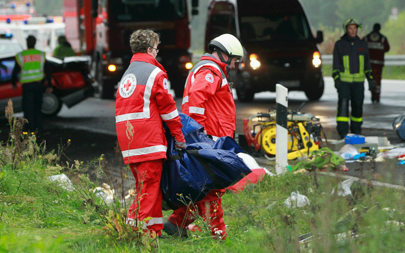 Rescue workers carry equipment near a tour bus that crashed into a concrete bridge support on the A10 highway near Berlin, Germany. According to police at least 11 people were killed and seven seriously injured. (GETTY IMAGES)
