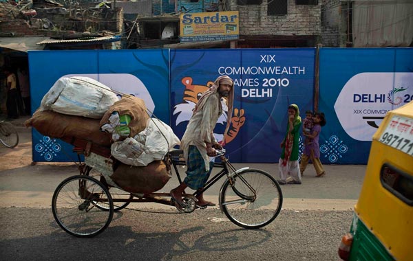 A garbage collecter passes by boards advertising the Commonwealth Games in New Delhi, India. (AP)
