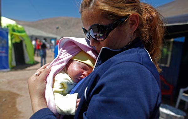 Elizabeth Segovia, right, holds her daughter Esperanza Ticona, the first baby of trapped miner Ariel Ticona, at the camp where relatives wait for the rescue of trapped miners outside the San Jose mine near Copiapo, Chile. (AP)