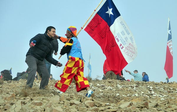 A man in a clown suit holding a Chilean flag celebrates with a TV reporter after one of the drills working to rescue the 33 trapped miners finally reached their shelter in the San Jose mine, near Copiapo, Chile. (AFP)