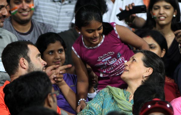 Congress Party President Sonia Gandhi (C/R) and her son Rahul Gandhi (C/L) speak with a young spectator as they sit in the stands  during the field hockey match between India and Pakistan for the XIX Commonwealth Games at The Major Dhyan Chand National Stadium in New Delhi. (AFP)