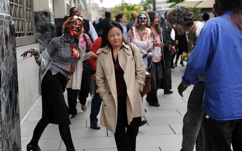 A woman on her way to work is surrounded by a group of actors portraying zombies to promote the new TV series "The Walking Dead" on the AMC channel on October 26, 2010 outside the Metro Center subway entrance in Washington, DC. (AFP)