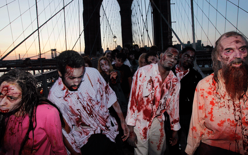 Costumed actors, promoting the Halloween premiere of the AMC television series "The Walking Dead", shamble along the Brooklyn Bridge while posing for pictures in New York. (AP)