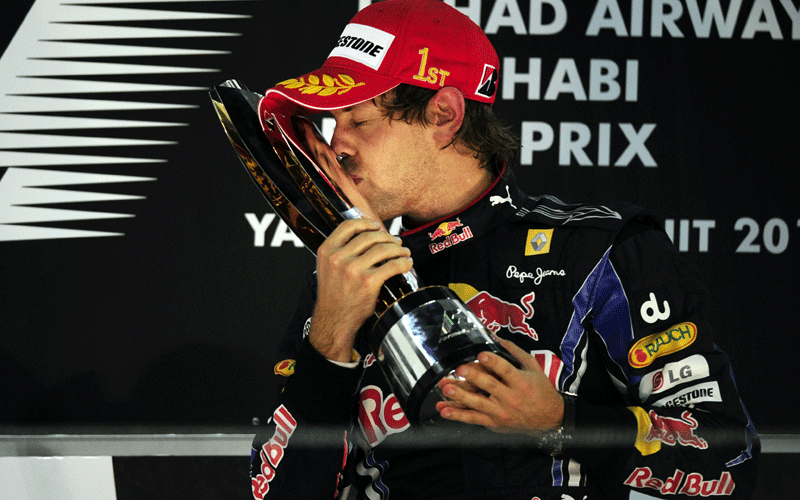 Red Bull's German driver Sebastian Vettel kisses his trophy on the podium of the Yas Marina circuit in Abu Dhabi, after the Abu Dhabi Formula One Grand Prix. Vettel won the race and the 2010 drivers' world championship.  (AFP)