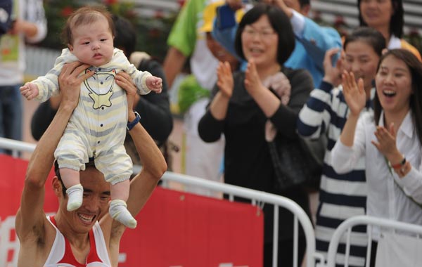 Ji Youngjun of South Korea holds aloft his child after winning the men's marathon at the triathlon venue during the 16th Asian Games in Guangzhou. (AFP)