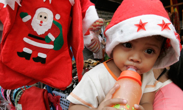 A baby girl wearing a Santa hat and sucks from her feeding bottle as they attend to their sidewalk stall in Manila, Philippines. With the approaching Christmas, vendors took advantage of the city government's leniency on selling on sidewalks. (AP)