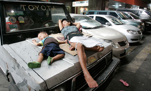 A woman sleeps beside a little boy on top of a car after preparing their merchandise early in the morning in Manila, Philippines. With the approaching Christmas, vendors took advantage of the city government's leniency on selling on sidewalks. (AP)