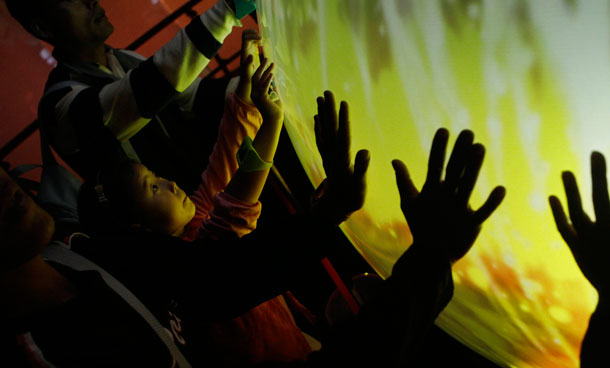 Visitors to the Taipei International Flora Exposition place their hands on a light sensitive globe to create audio and video displays at the Pavilion of Dreams highlighting Taiwan's innovation and technology, in Taipei, Taiwan. Already recognized as a supplier of smartphone and computer components to global technology companies, Taiwan wants to use the pavilion to highlight its capacity for product innovation in the increasingly competitive high-tech world, said Hsueh Wen-chen, head of the government-funded creativity center that designed the popular pavilion. (AP)