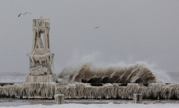 The large waves pounds the shore as the ice covers the pier in Chicago. High wind and frigid temperatures continue after a winter storm pummeled Illinois with snow and wind over the weekend. (AP)