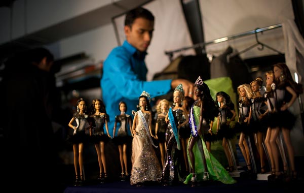 A contestant places his Barbie doll on a table during the Miss Barbie Venezuela 2010 beauty pageant in Caracas. (REUTERS)