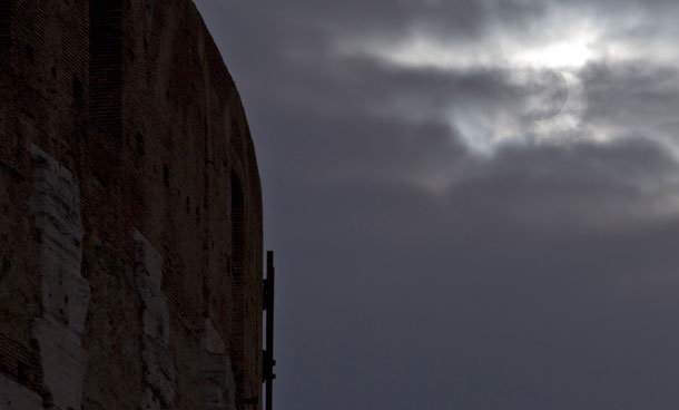 A partial solar eclipse is partially seen at top right through the clouds past the ancient Colosseum, in Rome, Italy, Tuesday, Jan. 4, 2011.(AP)
