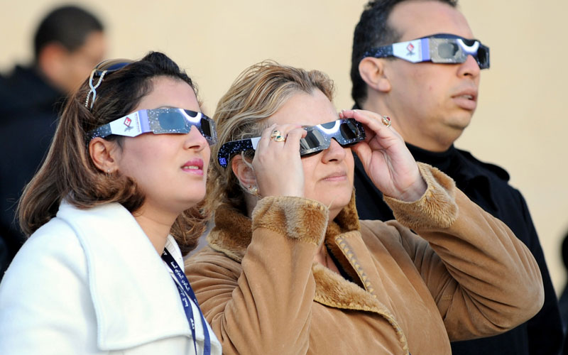 People wear special glasses as they watch the first partial solar eclipse of 2011 in Tunis. A solar eclipse happens when the Moon swings between the Earth and the Sun. (AFP)