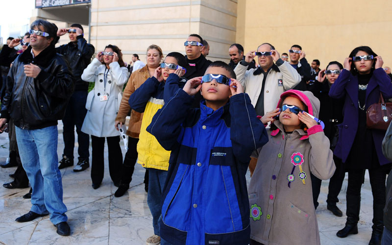 Tunisians observe the world's first partial solar eclipse of 2011 using a telescope in Tunis. Today's partial eclipse occurred when a fraction of the Moon obscured the Sun, making it seem -- in clear skies -- as if a "bite" had been taken out of the solar face. (AFP)