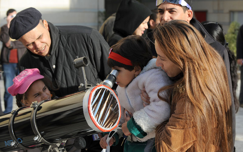 Tunisians observe the world's first partial solar eclipse of 2011 using a telescope in Tunis. Today's partial eclipse occurred when a fraction of the Moon obscured the Sun, making it seem -- in clear skies -- as if a "bite" had been taken out of the solar face. (AFP)