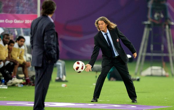 Qatar's coach Bruno Metsu (R) reaches out to stop the ball as Uzbekistan's coach Vadim Abramov looks on during their 2011 Asian Cup Group A soccer match at Khalifa stadium in Doha. (REUTERS)