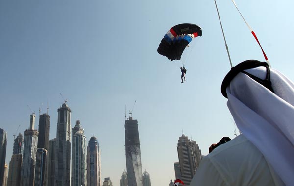An emirati man takes pictures of a member of the Armee Francaise team with Dubai's skyscrapers in the background during the Gulf emirate's 2nd International Parachuting Championship and Gulf Cup 2011. (AFP)
