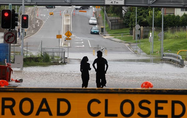 Australian students Gyan Poudel (R) and Sanjita Dhakai (L) walk through a flooded road at the suburb of Toombul, north of Brisbane. Flash floods ripped through northeast Australia, killing at least one person as they swept cars and pedestrians into rapids so strong they felled trees and caused landslides. (AFP)