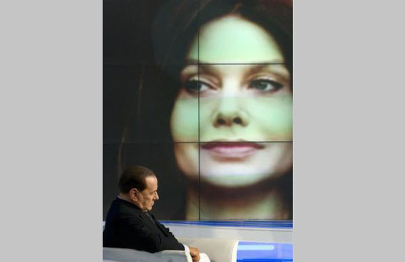 Italy's Prime Minister Silvio Berlusconi sits near an image of his wife Veronica Lario during the taping of the television program Porta a Porta ("Door to door" in Italian) in Rome. (REUTERS)