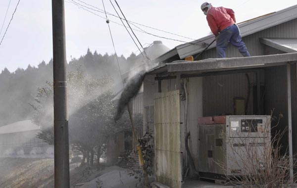 A masked man shovels volcanic ash from a roof of his residence in Miyakonojo, near Mount Shinmoedake in the Kirishimna range on Japan's southernmost main island of Kyushu. (AP)