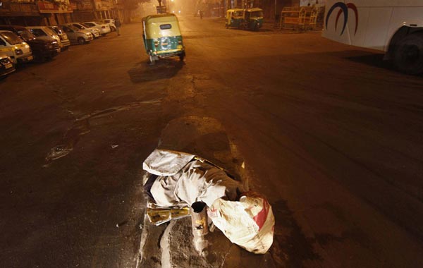 A homeless covered in a blanket and plastic sheets sleeps on a road divider on a roadside in a cold morning in the old quarters of Delhi January 13, 2011. According to local media reports, there are over 67,000 homeless in Delhi, of whom 15 percent are women and 10 percent children. (REUTERS)