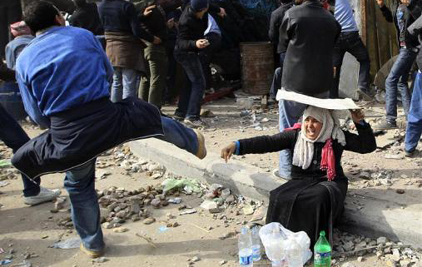 A woman opposition supporter takes shelter while providing water during rioting with pro-Mubarak demonstrators near Tahrir Square in Cairo. (REUTERS)