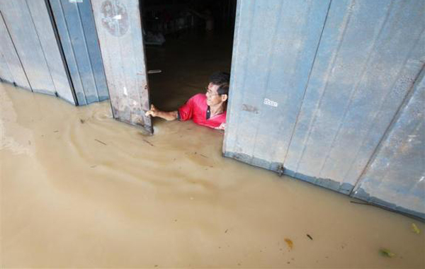 A trader closes his flooded shop in the village of Panchor, south of Kuala Lumpur. (REUTERS)