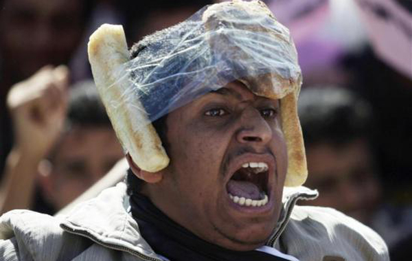 An opposition supporter with pieces of bread taped onto his head shouts slogans during an anti-government protest in Sanaa. (REUTERS)