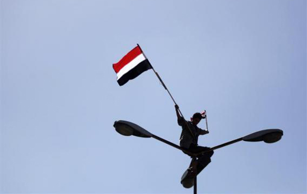 An opposition supporter waves Yemen's national flags while on sitting on a lamppost during an anti-government protest in Sanaa. (REUTERS)