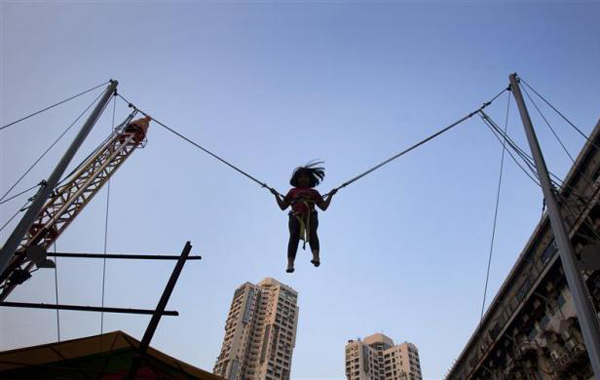 Zara, 7, plays suspended from wires on a trampoline at a fun fair outside a shopping mall in Mumbai. (REUTERS)