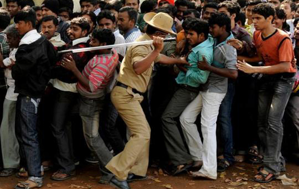 A policeman uses a stick to move men back into a queue for tickets for the India and England Group B cricket World Cup match at the M. Chinnaswamy Stadium in Bangalore February 24, 2011. Thousands of fans who had camped outside the stadium to buy just 4,000 tickets for Sunday's World Cup showdown between India and England clashed with police on Thursday, local media reported. (REUTERS)
