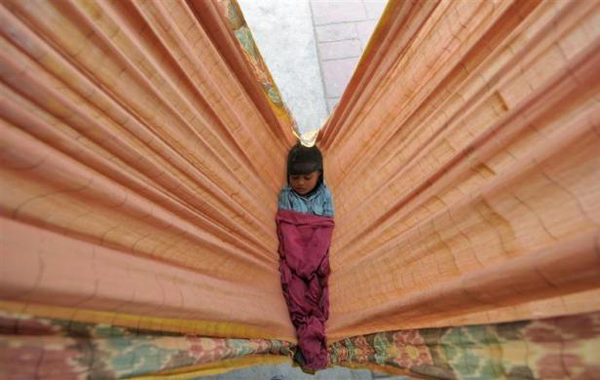 A child of a commuter sleeps in a hammock at a railway station in the southern Indian city of Hyderabad February 25, 2011. (REUTERS)