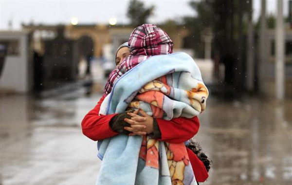 A Tunisian woman holds her child as she crosses the border into Tunisia at the border crossing of Ras Jdir after fleeing unrest in Libya February 23, 2011. (REUTERS)