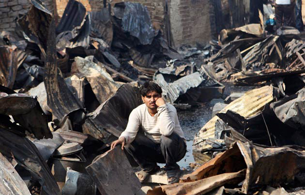 A resident sits near the rubble of his burnt home at a slum in Mumbai. (REUTERS)